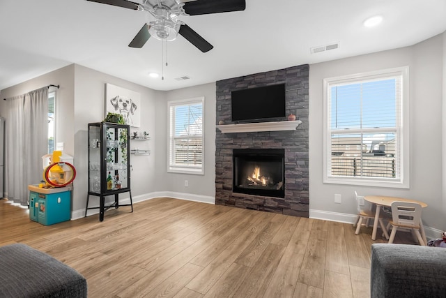 interior space with visible vents, baseboards, a fireplace, ceiling fan, and wood finished floors