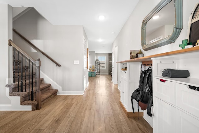 corridor featuring light wood finished floors, stairs, recessed lighting, and baseboards