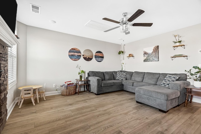 living room featuring light wood-style flooring, baseboards, ceiling fan, and visible vents