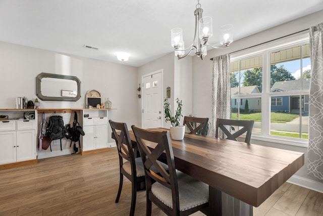 dining room with baseboards, visible vents, light wood-style flooring, and a chandelier