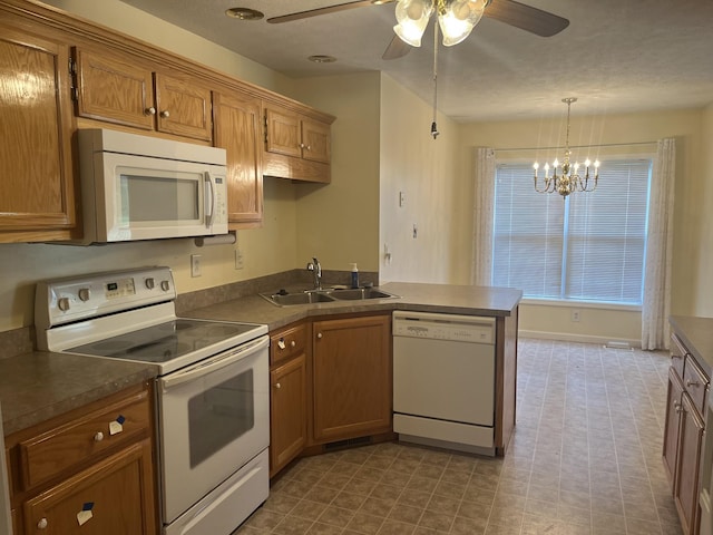 kitchen with a sink, ceiling fan with notable chandelier, a peninsula, brown cabinets, and white appliances