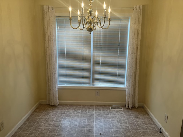 unfurnished dining area with baseboards, a notable chandelier, and visible vents