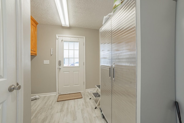 entryway with baseboards, light wood-type flooring, and a textured ceiling