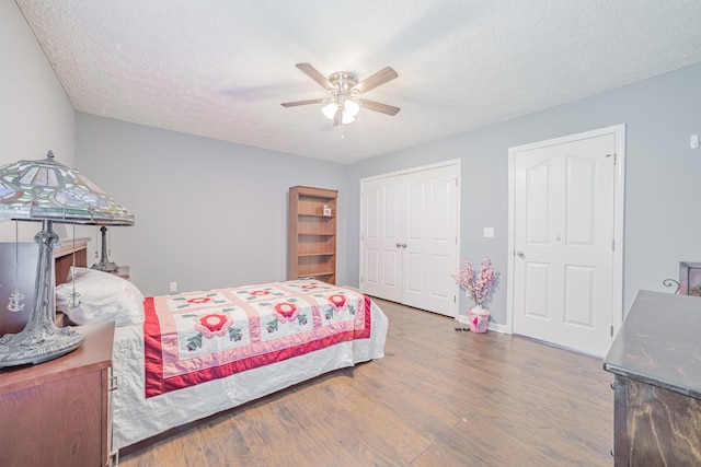 bedroom with a closet, baseboards, ceiling fan, a textured ceiling, and wood finished floors