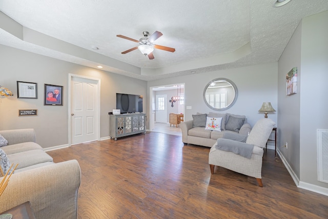 living room featuring ceiling fan, a textured ceiling, wood finished floors, and a raised ceiling