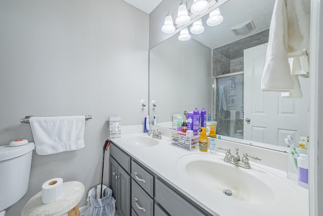 bathroom featuring a sink, visible vents, toilet, and a stall shower