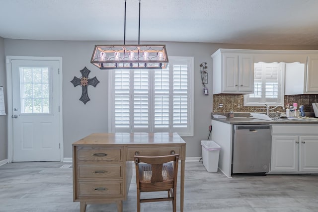 kitchen with tasteful backsplash, stainless steel dishwasher, baseboards, and white cabinetry