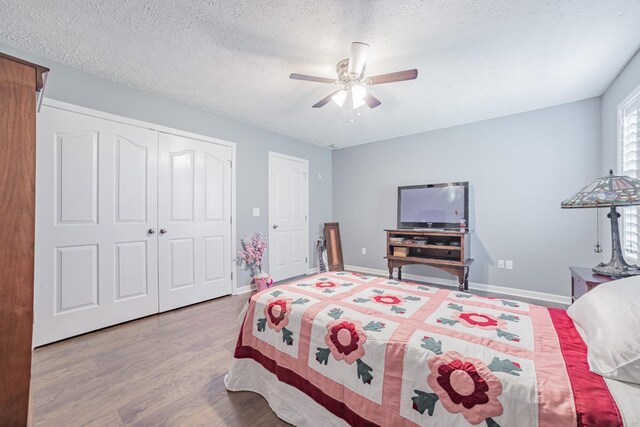 bedroom with a closet, baseboards, a textured ceiling, a ceiling fan, and wood finished floors