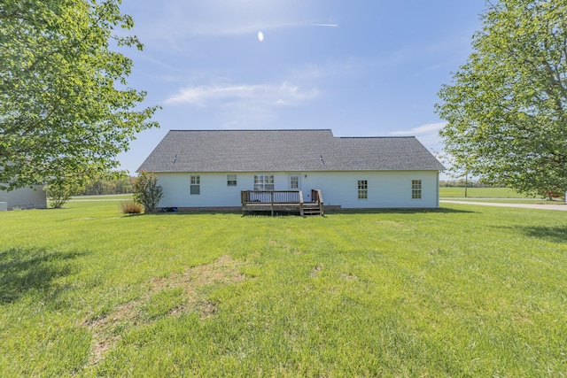 rear view of property featuring a yard, a deck, and roof with shingles