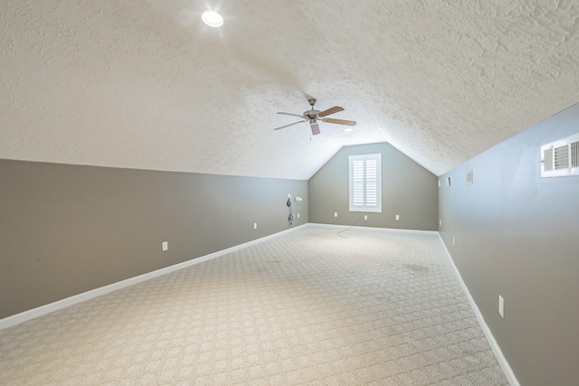bonus room with a textured ceiling, ceiling fan, baseboards, and lofted ceiling
