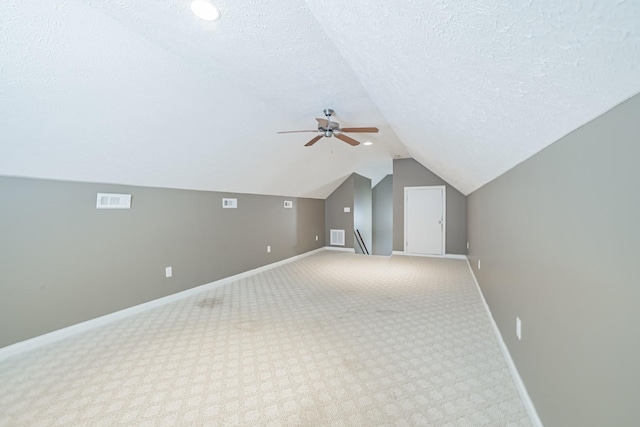 additional living space with visible vents, baseboards, a ceiling fan, a textured ceiling, and vaulted ceiling
