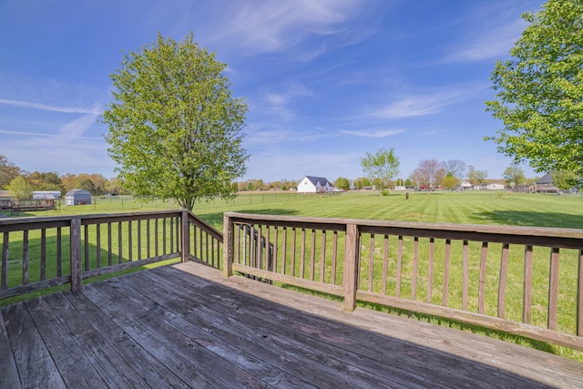 wooden terrace with a rural view, a fenced backyard, and a lawn