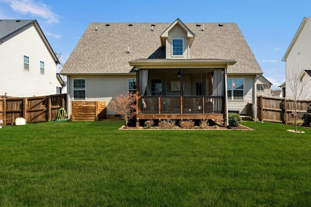 rear view of house with a fenced backyard, ceiling fan, a lawn, and roof with shingles