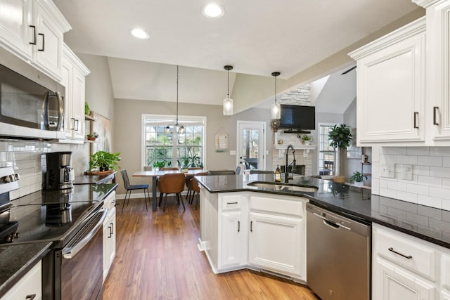 kitchen with a sink, decorative backsplash, lofted ceiling, appliances with stainless steel finishes, and recessed lighting