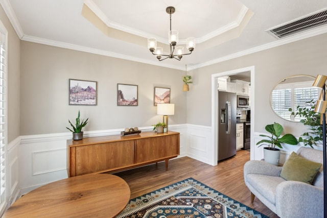 living area featuring crown molding, a notable chandelier, dark wood-type flooring, and visible vents