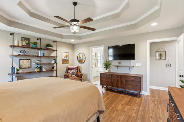 bedroom featuring ornamental molding, light wood-style flooring, and a raised ceiling