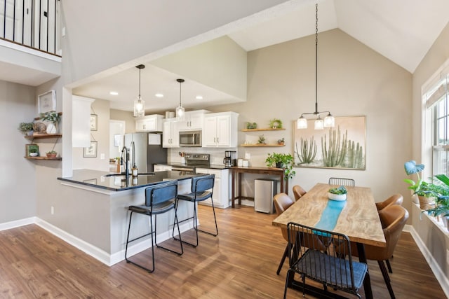kitchen featuring high vaulted ceiling, dark countertops, open shelves, and stainless steel appliances