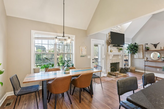 dining area with plenty of natural light, a brick fireplace, wood finished floors, and baseboards