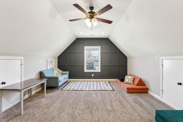 sitting room featuring carpet, vaulted ceiling, visible vents, baseboards, and ceiling fan
