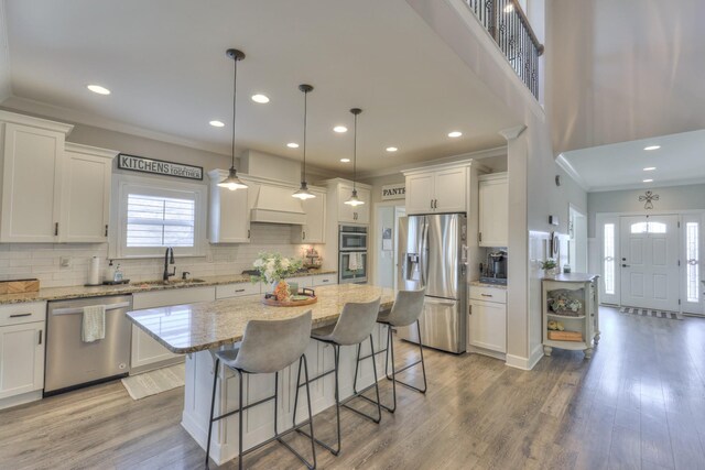127 Waters Hill Cir, Lebanon, TN 37087 - kitchen with white cabinets, light wood-style flooring, ornamental molding, appliances with stainless steel finishes, and a sink