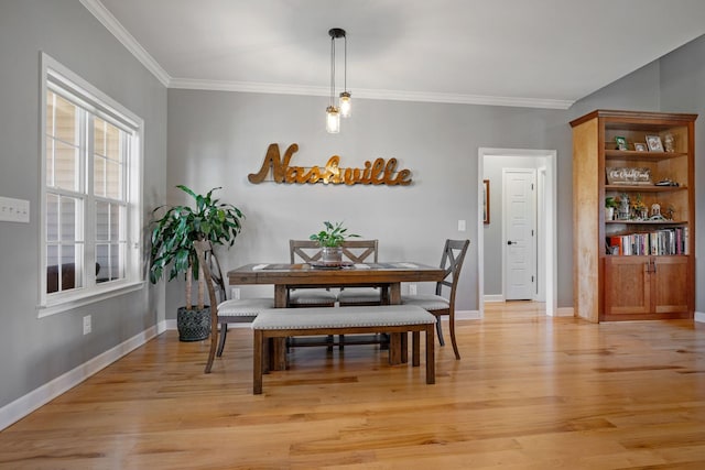 dining area featuring baseboards, crown molding, and light wood finished floors