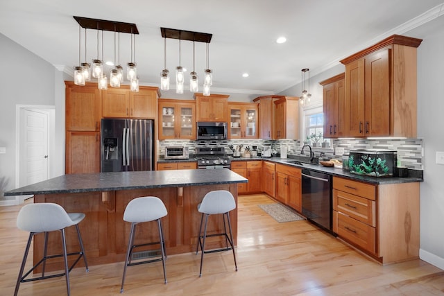 kitchen with ornamental molding, a sink, a kitchen island, and appliances with stainless steel finishes