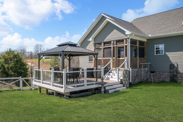 rear view of house featuring a sunroom, fence, a wooden deck, a gazebo, and a yard