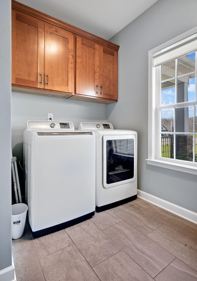 washroom with baseboards, cabinet space, and independent washer and dryer