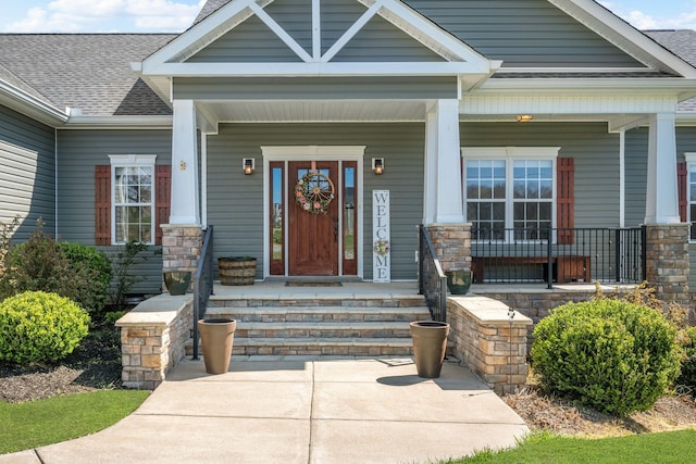 property entrance with stone siding, a porch, and a shingled roof