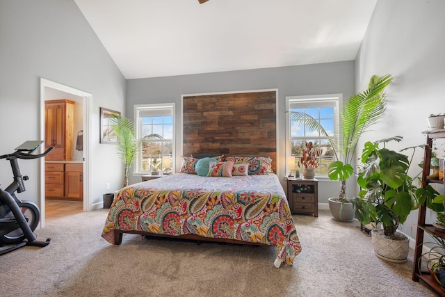 carpeted bedroom featuring high vaulted ceiling, ensuite bath, and baseboards