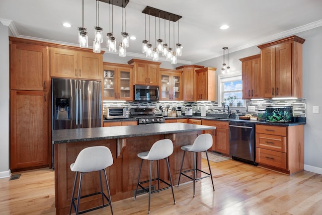 kitchen featuring dark countertops, a sink, stainless steel appliances, and crown molding