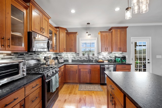 kitchen with crown molding, a sink, stainless steel appliances, and brown cabinets
