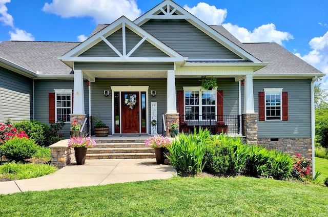 craftsman-style house featuring covered porch, a front yard, and roof with shingles