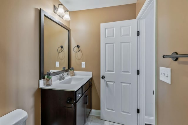 bathroom featuring tile patterned flooring, vanity, baseboards, and toilet