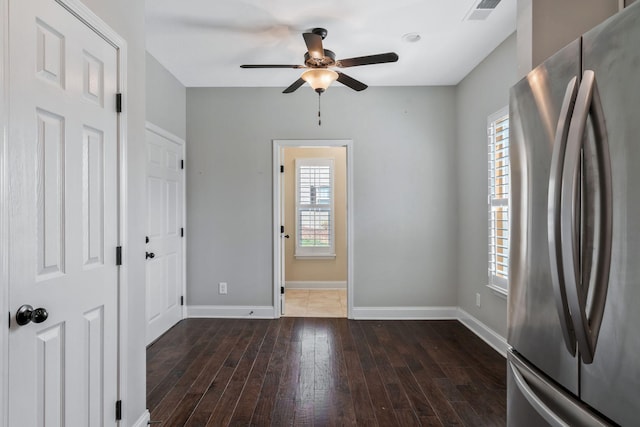 interior space with baseboards, a ceiling fan, visible vents, and hardwood / wood-style flooring