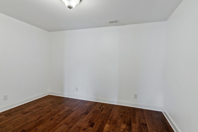empty room with wood-type flooring, visible vents, and baseboards