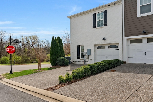 multi unit property featuring an attached garage, driveway, and brick siding