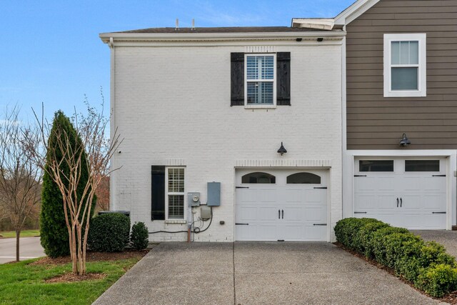view of front of home featuring an attached garage, driveway, and brick siding