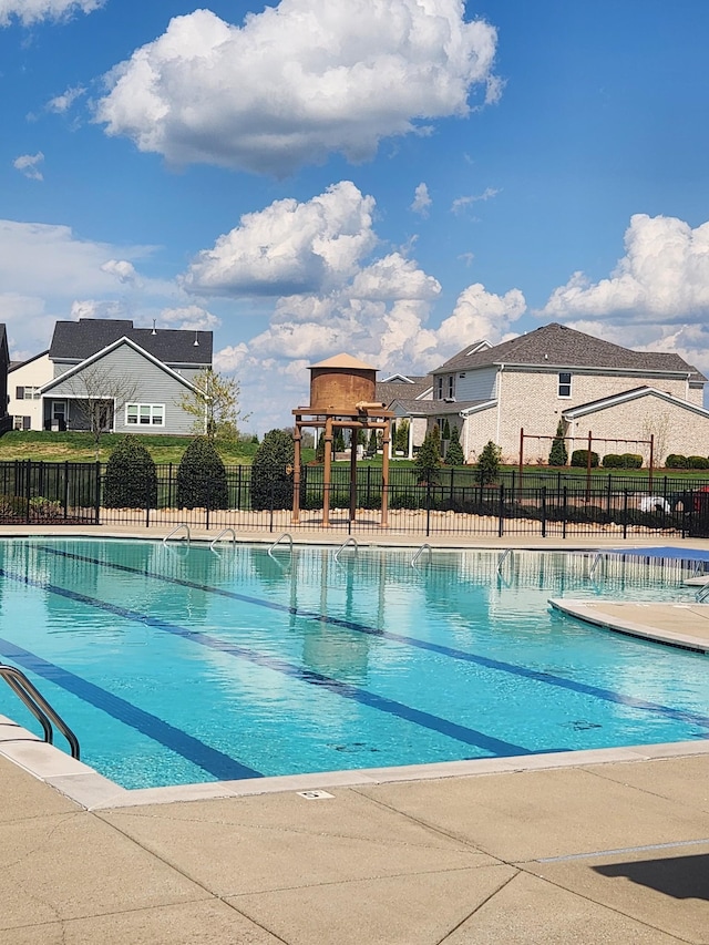 view of swimming pool featuring fence and a residential view