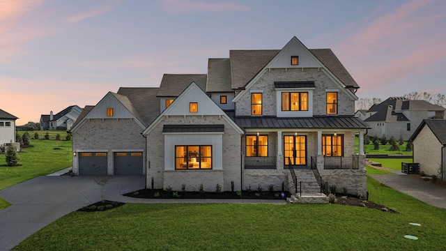 modern inspired farmhouse featuring covered porch, concrete driveway, a standing seam roof, and a yard