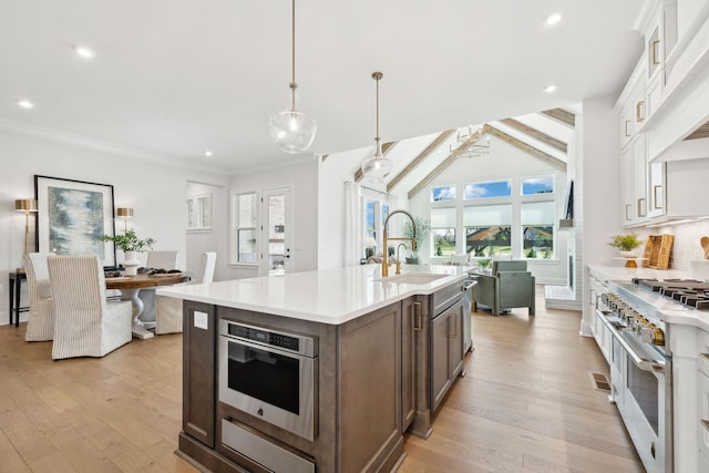 kitchen featuring light countertops, an island with sink, stainless steel appliances, and light wood-type flooring
