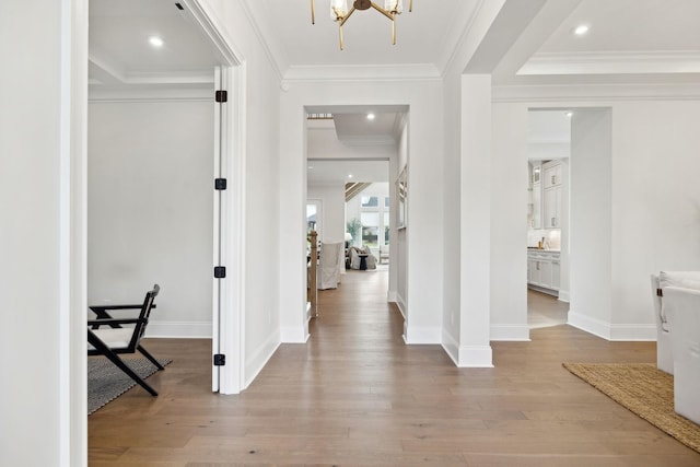 foyer entrance with baseboards, light wood-type flooring, ornamental molding, and an inviting chandelier