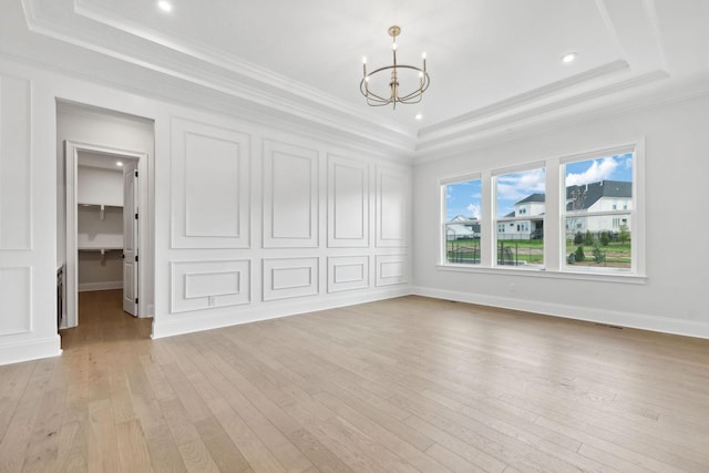 spare room featuring ornamental molding, a chandelier, and a raised ceiling