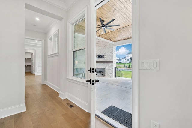 hallway with baseboards, visible vents, crown molding, and hardwood / wood-style flooring