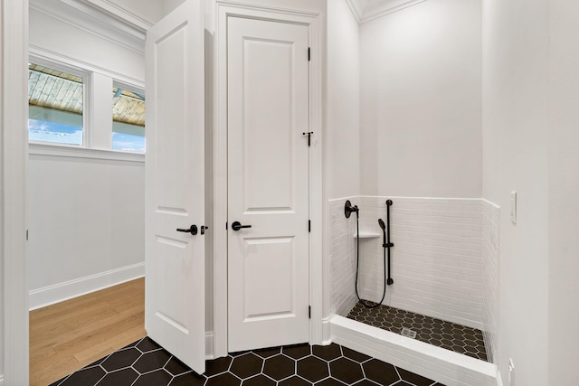 bathroom featuring ornamental molding, tiled shower, and wood finished floors