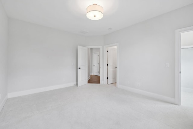 unfurnished bedroom featuring a spacious closet, carpet floors, and baseboards