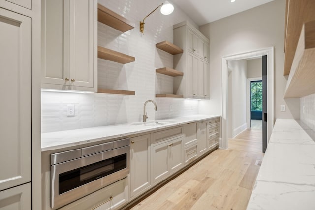 8115 Devens Dr, Brentwood, TN 37027 - kitchen with tasteful backsplash, open shelves, stainless steel microwave, a sink, and light wood-style floors