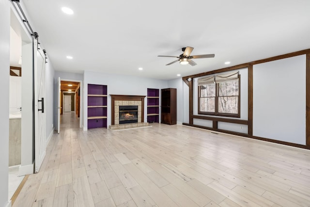 3755 Bear Hollow Rd, Joelton, TN 37080 - unfurnished living room featuring a fireplace, a barn door, light wood-type flooring, ceiling fan, and recessed lighting