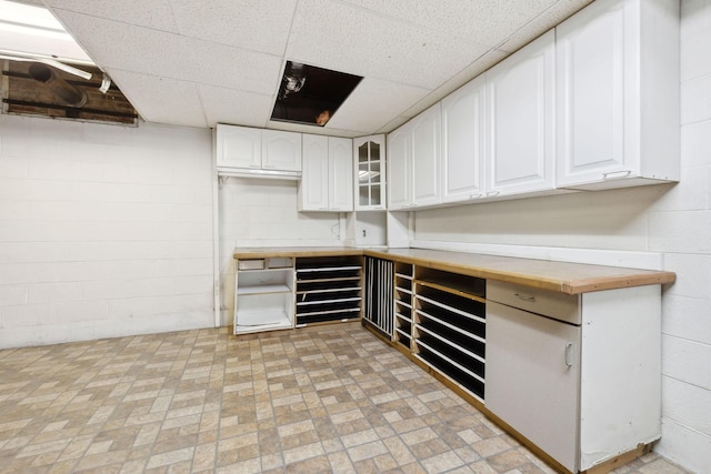 3755 Bear Hollow Rd, Joelton, TN 37080 - kitchen featuring glass insert cabinets, wood counters, concrete block wall, and white cabinets
