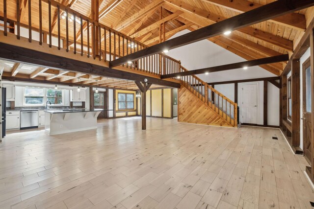 3755 Bear Hollow Rd, Joelton, TN 37080 - unfurnished living room featuring wood walls, stairs, light wood-style flooring, and beam ceiling
